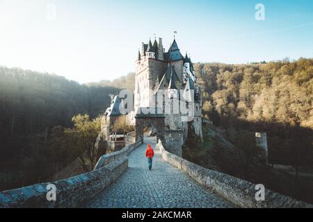 Vue panoramique de young explorer avec sac à dos en admirant la vue au célèbre château d'Eltz au lever du soleil à l'automne, Rheinland-Pfalz, Allemagne Banque D'Images