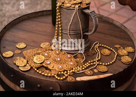Jack Sparrow.Pièces Pièces d'or artificiel et une décoration sur un tonneau en bois. Un mug rempli avec de l'or monnaie artificielle. Banque D'Images