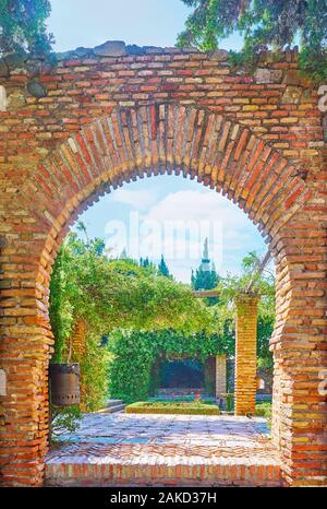 La vue sur le jardin luxuriant Alcazaba médiévale par l'arc en fer à cheval, Malaga, Espagne Banque D'Images