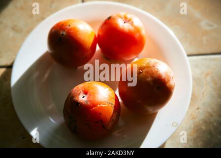 Plaqueminier de fruits sur une assiette blanche close-up Vue de dessus. Banque D'Images