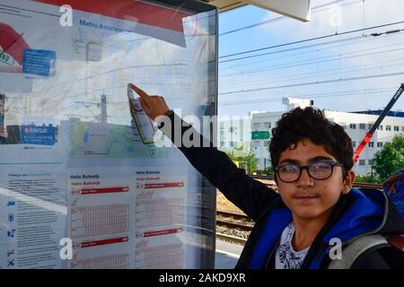 Amsterdam, Pays-Bas, août 2019. Un brown-haired woman with glasses points à un point sur le plan du métro. Banque D'Images