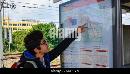 Amsterdam, Pays-Bas, août 2019. Un brown-haired woman with glasses points à un point sur le plan du métro. Banque D'Images