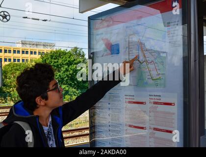 Amsterdam, Pays-Bas, août 2019. Un brown-haired woman with glasses points à un point sur le plan du métro. Banque D'Images