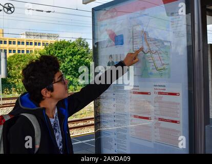 Amsterdam, Pays-Bas, août 2019. Un brown-haired woman with glasses points à un point sur le plan du métro. Banque D'Images