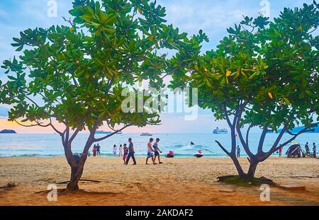 PATONG, THAÏLANDE - Mai 1, 2019 : les vacanciers à pied le long de la plage centrale de station avec ombragé de figuiers et amarré jet le 1 mai en P Banque D'Images