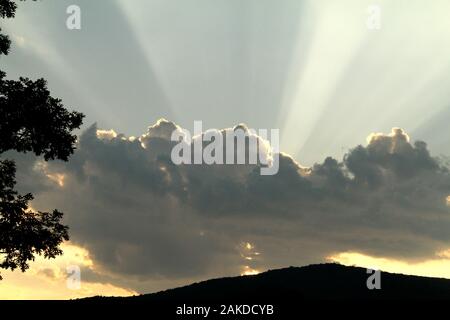 Les rayons du soleil émergeant de derrière un nuage avant le coucher du soleil Banque D'Images