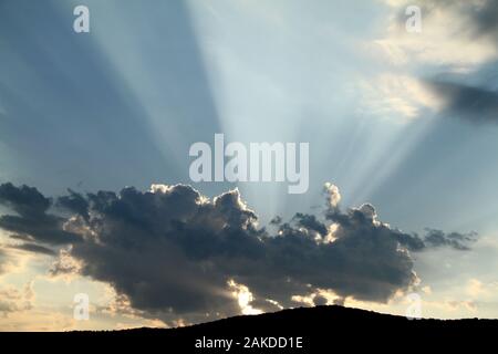 Les rayons du soleil émergeant de derrière un nuage avant le coucher du soleil Banque D'Images