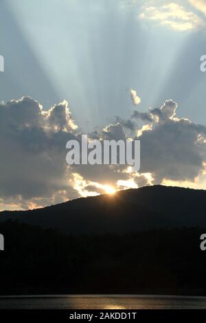 Les rayons du soleil émergeant de derrière un nuage avant le coucher du soleil Banque D'Images