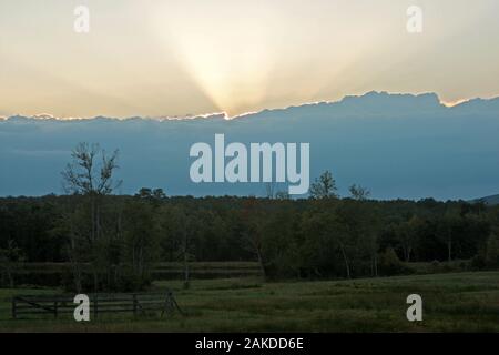 Les rayons du soleil sortent de derrière une grande masse de nuages Banque D'Images