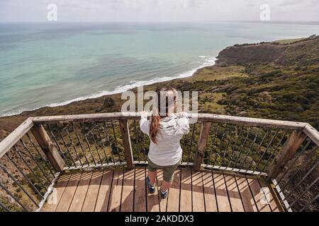 Une femelle regarde l'océan depuis un point de vue élevé, Raglan, Nouvelle-Zélande Banque D'Images