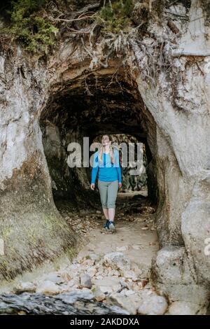 Une jeune femme marche dans une grotte, le parc national d'Abel Tasman Banque D'Images