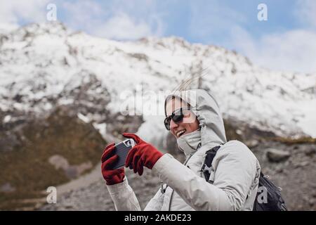 Femme randonneur utilise la caméra de téléphone cellulaire lors de journées venteuses en montagne. Banque D'Images