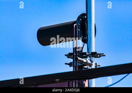 Close up détails d'une station de base du réseau cellulaire, l'équipement de communications électroniques est considérée vissés et boulonnés à un poteau en acier contre un ciel bleu Banque D'Images