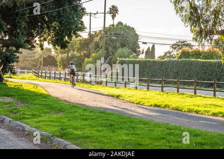 Une piste cyclable très utilisé en fin d'après-midi avec une lumière dramatique bike rider homme à cheval sur le chemin. Banque D'Images