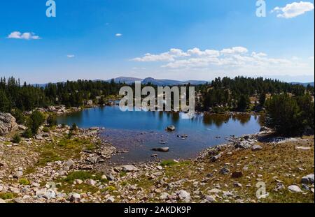 Les eaux d'un lac de haute montagne reflètent les rochers et la forêt qui l'entoure. Banque D'Images