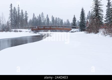 La neige qui tombe sur la passerelle au-dessus du ruisseau du policier à Canmore, Alberta, Canada Banque D'Images