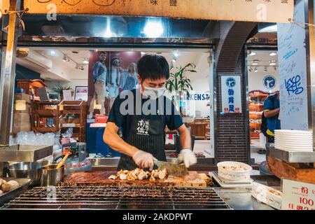 Un homme braise et hache des champignons d'huîtres en morceaux au Shi Lin Night Market, Taipei, Taïwan Banque D'Images