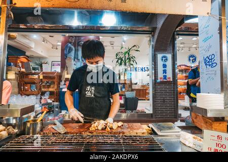 Un homme braise et hache des champignons d'huîtres en morceaux au Shi Lin Night Market, Taipei, Taïwan Banque D'Images