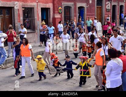 Les enfants mexicains dans le défilé de la place locale. Bâtiments entourant El Jardín Allende Parc de San Miguel de Allende, Mexique. Site du patrimoine mondial. Banque D'Images