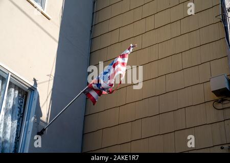 Tattered United States drapeau américain accroché en face de la maison de banlieue Banque D'Images