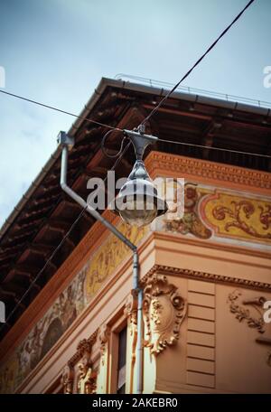 Old vintage lampe de rue sur le croisement des fils d'antenne au-dessus de la rue avec un bel immeuble ancien à l'architecture ornementale dans l'arrière-plan Banque D'Images
