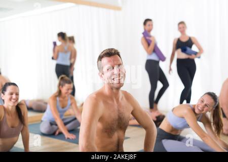 Portrait d'un homme gai sex instructeur de yoga yoga détente après avoir donné à l'important groupe de personnes intéressantes sportive. Mode de vie sain et actif Banque D'Images