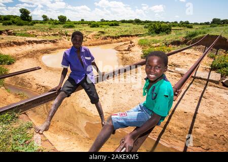 Enfants jouant sur les voies du pont de chemin de fer emportée par l'inondation Janvier 2015 de quitter les pistes en suspension dans l'air, près de Bangula. Le Malawi. Mars. Banque D'Images