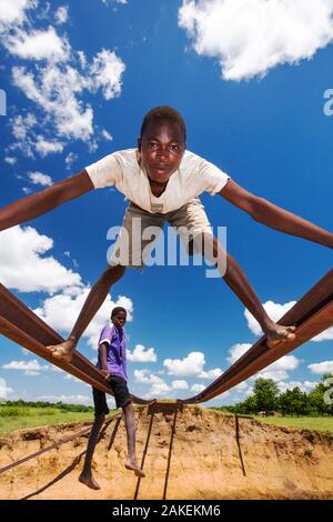 Enfants jouant sur les voies du pont de chemin de fer emportée par l'inondation Janvier 2015 de quitter les pistes en suspension dans l'air, près de Bangula. Le Malawi. Mars. Banque D'Images