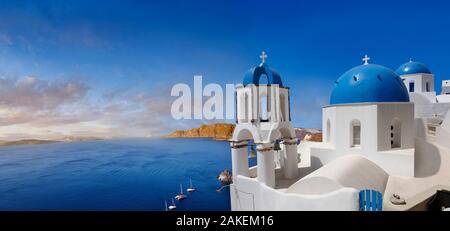 Vue panoramique sur les églises orthodoxes grecques traditionnelles d'Oia (Ia), Cyclades île de Thira, Santorin, Grèce. Le règlement de l'Eid a été men Banque D'Images