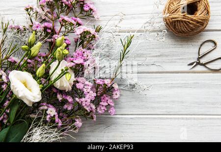 Lieu de travail : fleuriste fleurs et accessoires sur un whitw table en bois. Mise à plat. Banque D'Images