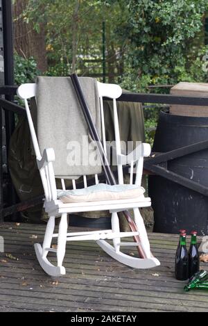 Rocking chair en bois ancien et shot gun avec de la bière sur une terrasse en bois dans l'ouest sauvage Banque D'Images