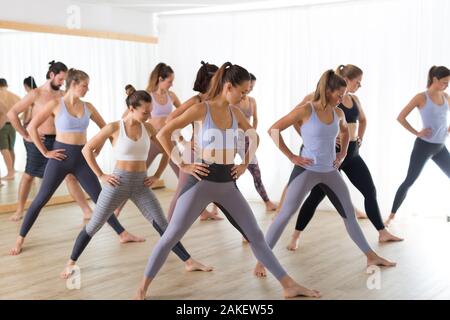 Groupe de jeunes gens de attrayant sportive authentique studio de yoga, la pratique du yoga leçon avec instructeur. Mode de vie sain et actif, working out in gym Banque D'Images