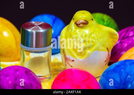 Petite salière en regard d'un poussin d'argile et les oeufs de Pâques colorés Banque D'Images