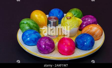 Petite salière en regard d'un poussin d'argile et les oeufs de Pâques colorés Banque D'Images