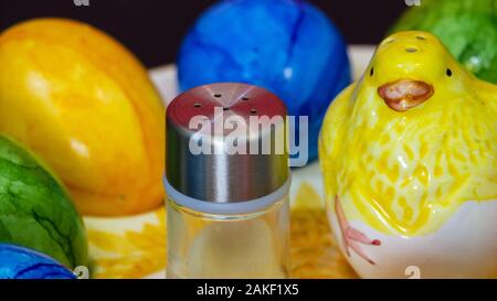 Petite salière en regard d'un poussin d'argile et les oeufs de Pâques colorés Banque D'Images