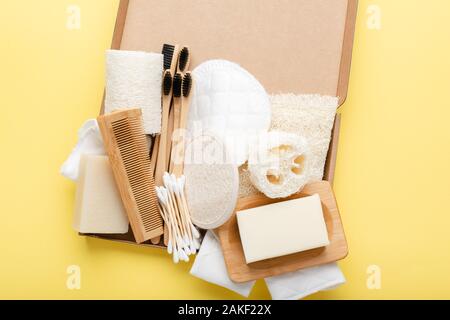 Zéro déchets avec soins naturels accessoires sur jaune. Brosses à dents, savon artisanal en bambou pains shampooings, coton-tiges, les produits hygiéniques tampons luffa, vue du dessus, selective focus Banque D'Images