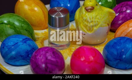 Petite salière en regard d'un poussin d'argile et les oeufs de Pâques colorés Banque D'Images