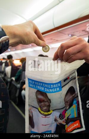 Un sac de collecte de dons caritatifs de l'UNICEF est retiré par un membre de l'équipage de cabine du Royaume-Uni d'un avion d'avion pour recueillir un petit argent et argent en espèces auprès des passagers. L'argent recueilli sera dans la lutte contre la poliomyélite. ROYAUME-UNI (115) Banque D'Images