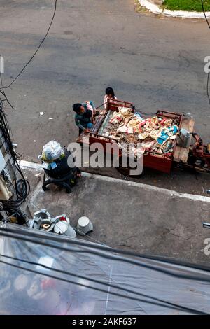 Un sans-abri est la famille pauvres chasse réunis autour d'un véhicule utilisé pour le transport des matières recyclables dangereuses sur une rue de ville de Kampong Cham, au Cambodge. Banque D'Images