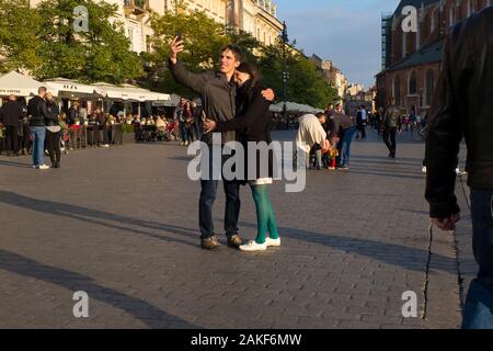Un jeune couple heureux prend une photo égoïste sur la place principale de Cracovie, en Pologne Banque D'Images