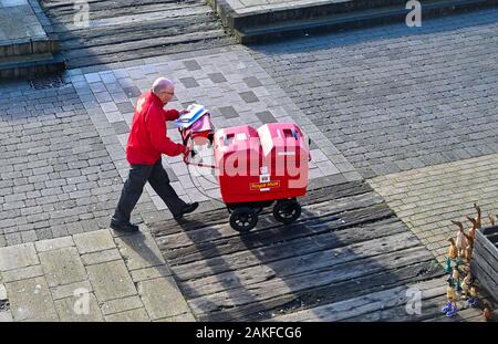 Royal Mail postman travaillant et marchant le long du front de mer de Brighton au Royaume-Uni Banque D'Images