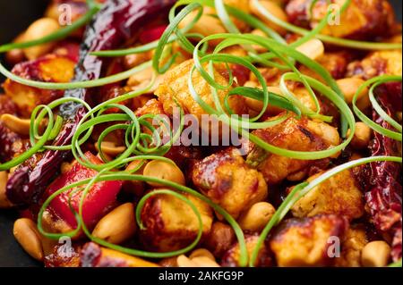 Kung Pao Paneer à fond en ardoise noire. Kung Pao Paneer est une version végétarienne de plat chinois Sichuan Gong Bao avec paneer fromage, arachides, chill Banque D'Images