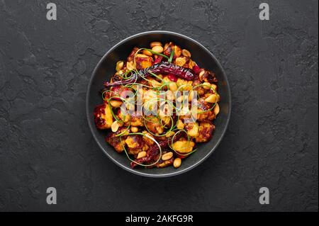 Kung Pao Paneer à fond en ardoise noire. Kung Pao Paneer est une version végétarienne de plat chinois Sichuan Gong Bao avec paneer fromage, arachides, chill Banque D'Images