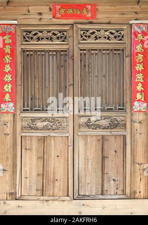 La vieille porte de bois sculpté de style traditionnel avec des couplets de la fête du printemps pendant le nouvel an chinois. Banque D'Images