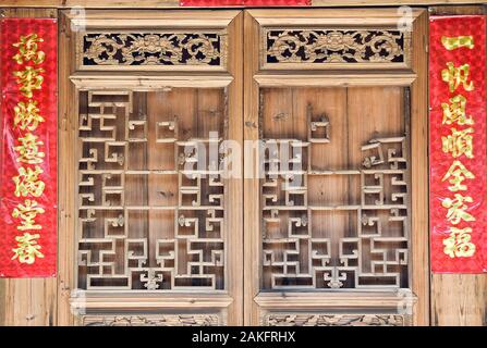 La vieille porte de bois sculpté de style traditionnel avec des couplets de la fête du printemps pendant le nouvel an chinois. Banque D'Images