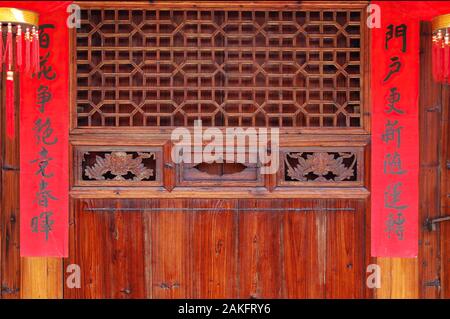 La vieille porte de bois sculpté de style traditionnel avec des couplets de la fête du printemps pendant le nouvel an chinois. Banque D'Images