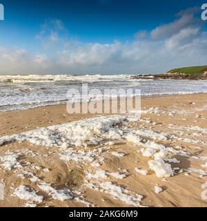 Spume ou sea foam à gauche sur la plage de Fistral par temps venteux à Newquay en Cornouailles. Banque D'Images