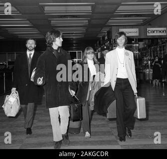 Les Beatles stars John Lennon (r), avec son épouse Cynthia Lennon derrière, et George Harrison à l'aéroport de Heathrow, Londres, avant de prendre l'avion pour l'Inde. Banque D'Images