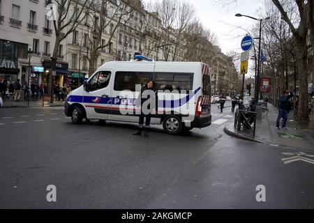 Véhicule de police stationné sur route et officier, bloquer la route de la circulation pendant la grève générale, en prévision de la manifestation, place Jeanne-Bohec, 75018 Paris, janvier 2020 Banque D'Images