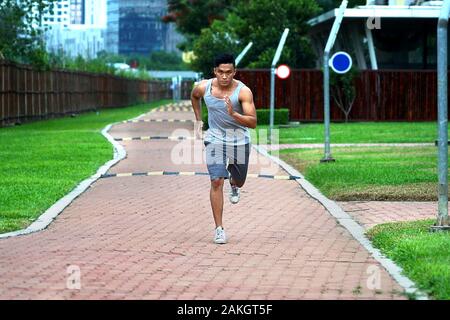 Les jeunes hommes asiatiques courir devant la caméra - Enthousiasme garçon faire du sport dans l'après-midi au campus Banque D'Images